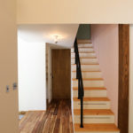 3：グレーピンクの壁とスチール手すりの階段。階段下は収納として有効活用